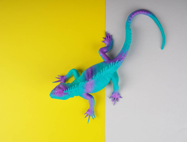 toy iguana lizard on a gray and yellow background, concept photo, space for text - Fotoğraf, Görsel