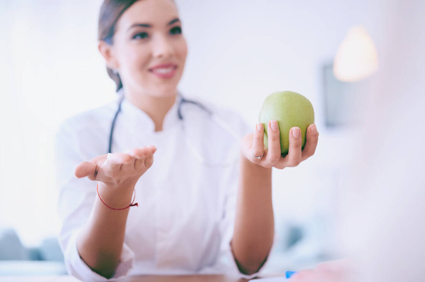 Női orvos tartja alma és tablettát, miközben megvitatják a beteg az irodában a kórházban. Kiváló minőségű fénykép - Fotó, kép