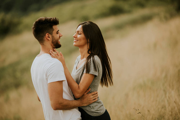Feliz joven pareja enamorada en el campo de hierba en un día de verano - Foto, imagen