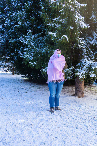 messa a fuoco selettiva di una ragazza adolescente che indossa una maschera e indossa una sciarpa rosa in solidarietà con la malattia del cancro al seno in una fredda giornata invernale circondata dalla neve - Foto, immagini