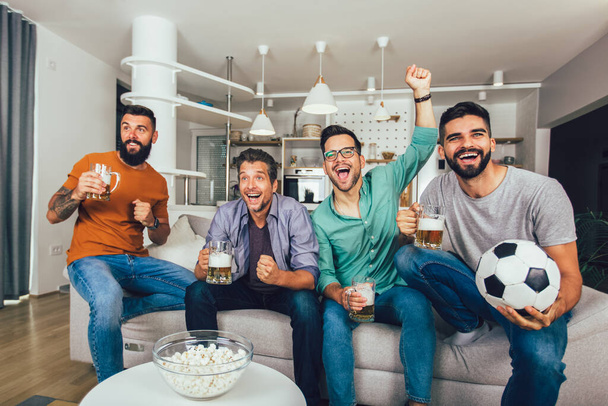 Amici felici e tifosi di calcio guardando il calcio in tv e celebrando la vittoria a casa - Foto, immagini