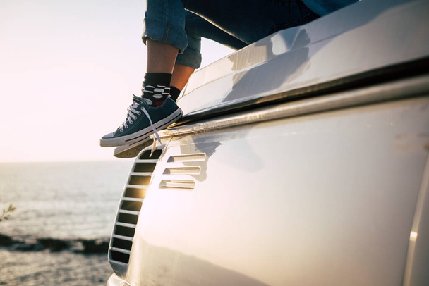 Primo piano concetto di persone di viaggio godere il mondo con un paio di scarpe da ginnastica blu e ragazza sedersi sul tetto del suo furgone  - Foto, immagini