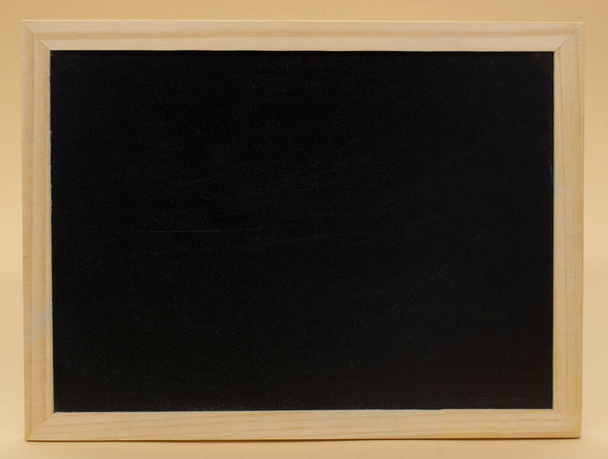 Realistic black blackboard in wooden frame isolated on beige background. Rubbed out dirty chalkboard. Background for school or restaurant design, menu - Fotografie, Obrázek