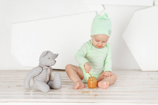 Babynahrungslöffelspielzeug im grünen Body-Anzug, Fütterungs- und Babynahrungskonzept - Foto, Bild