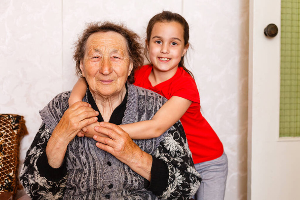 radosna młoda dziewczyna opiekuje się starszą kobietą w domu - Zdjęcie, obraz