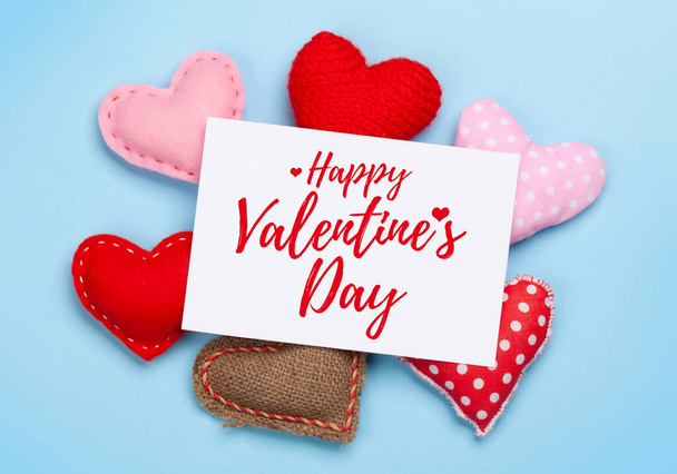 Valentines day greeting card over heart shaped decor on blue background. Top view flat lay - Foto, Imagem