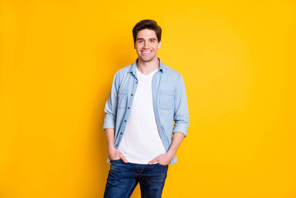Photo of nice-looking guy stand hands pockets wear blue shirt jeans isolated on yellow color background - Photo, Image