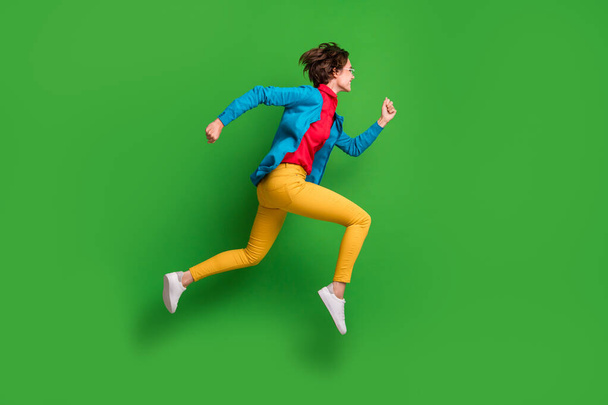 Full length body size side profile photo of jumping running girl in colorful clothes isolated on vibrant green color background - Фото, изображение
