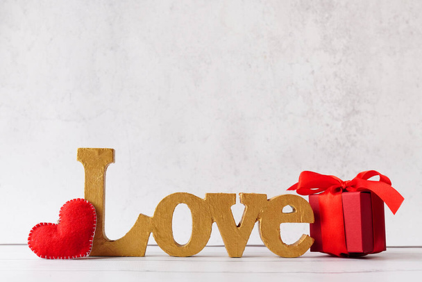 word Love, red Gift or present box with bow ribbon and heart on light stone background, greeting card for Valentines day. - Φωτογραφία, εικόνα