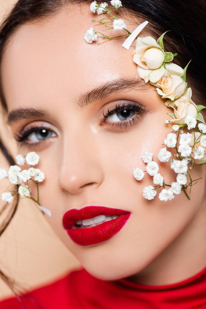 close up of woman with red lips and flowers on face looking at camera isolated on pink  - Foto, Imagen