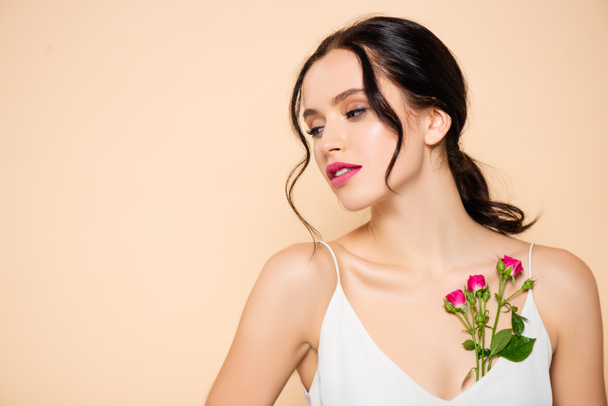 sensual young woman looking away near flowers isolated on pink  - Фото, зображення