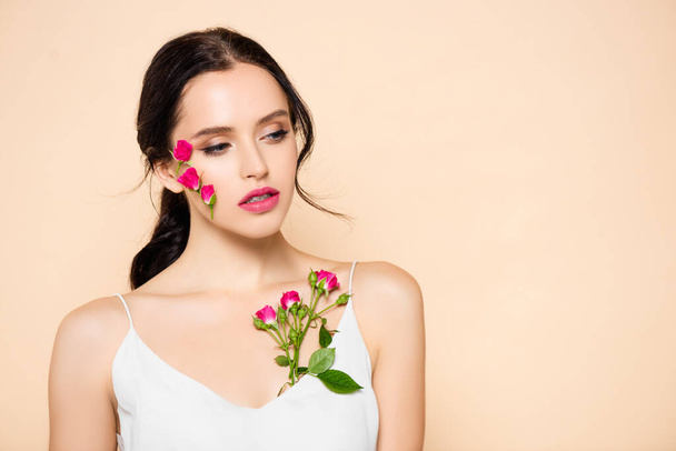 sensual young woman with flowers on face looking away isolated on pink  - Foto, Imagem