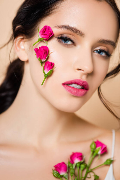 sensual woman with flowers on face looking at camera isolated on pink  - Foto, Imagem