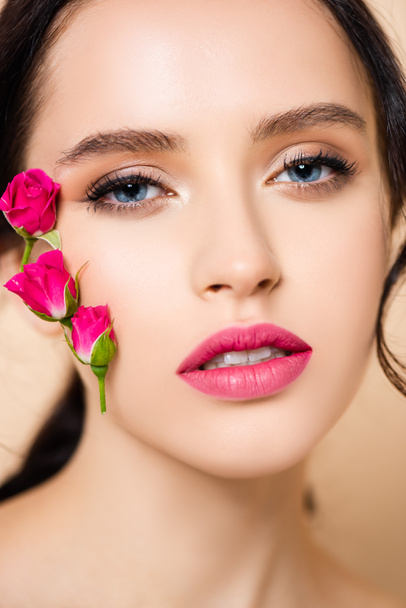 close up of sensual young woman with flowers on face looking at camera isolated on pink  - Fotoğraf, Görsel
