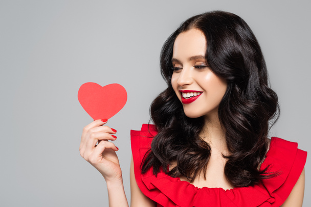 cheerful young woman holding red paper heart isolated on grey - Fotoğraf, Görsel