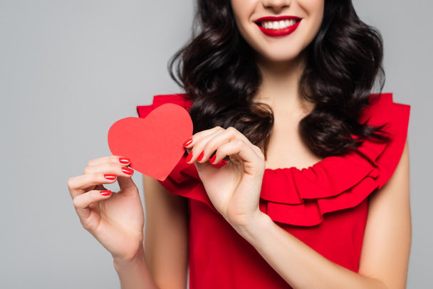 cropped view of cheerful young woman holding red paper heart isolated on grey - Foto, Imagem