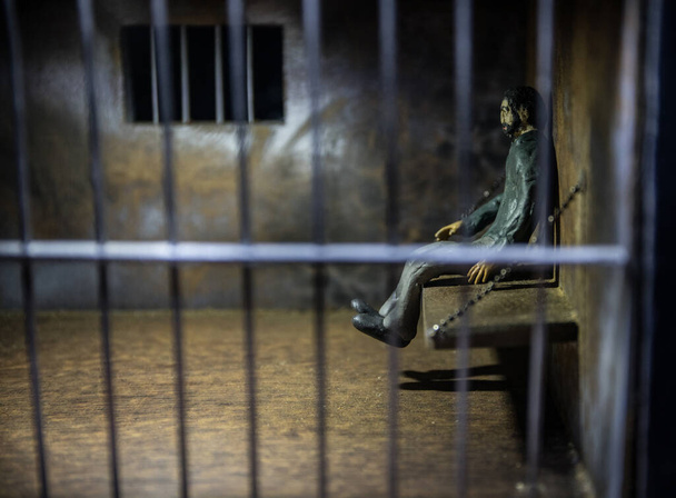 Człowiek w więzieniu za kratkami. Stare brudne więzienne miniatury grunge 'a. Ciemne więzienne wnętrze dekoracja twórcza. Skupienie selektywne - Zdjęcie, obraz