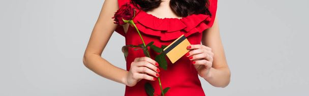 καλλιεργούμενη άποψη της γυναίκας που κατέχει κόκκινο τριαντάφυλλο και πιστωτική κάρτα που απομονώνονται σε γκρι, banner - Φωτογραφία, εικόνα