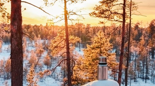 Thermos in the winter forest at sunset of the day with sunset. Winter tourism and travel concept - Fotografie, Obrázek