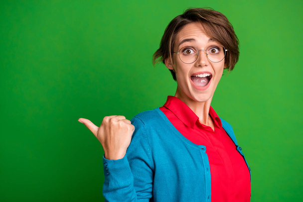 Photo portrait of shocked amazed female student pointing at blank space opened mouth isolated on vibrant green color background - Foto, imagen