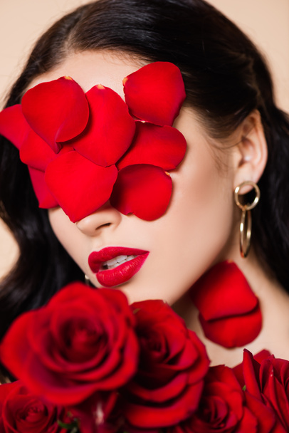 young brunette woman with petals on face and red roses - Foto, imagen