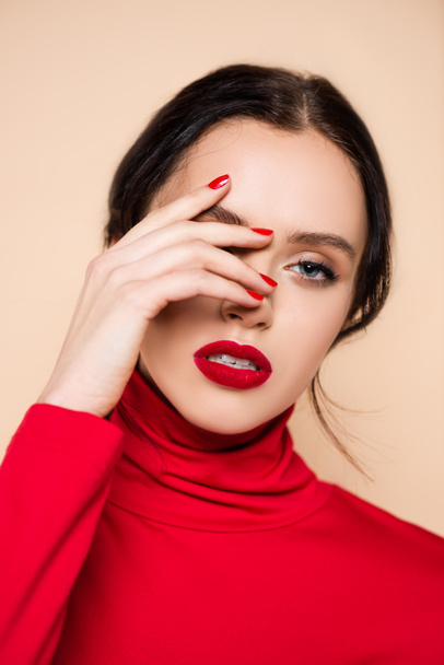 brunette young woman with red lips covering face with hand and looking at camera isolated on pink - Photo, Image