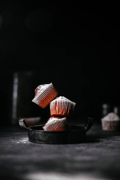 chocolate muffins with powdered sugar on a dark background - Photo, image