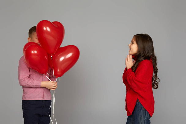 couple of little girl and boy with red heart balloons - 写真・画像