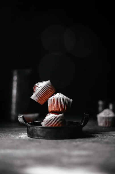 muffins de chocolate com açúcar em pó em um fundo escuro - Foto, Imagem