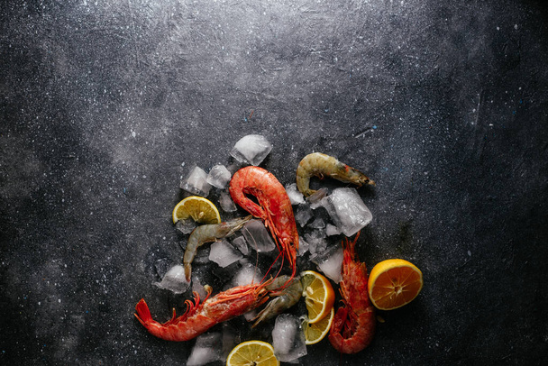 camarones en hielo con limón sobre un fondo gris - Foto, Imagen