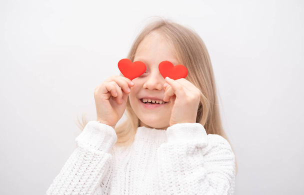 Portret van een schattig klein meisje met twee rode harten in haar handen. Valentijnsdag 8 maart, moederdag, vaderdag. - Foto, afbeelding
