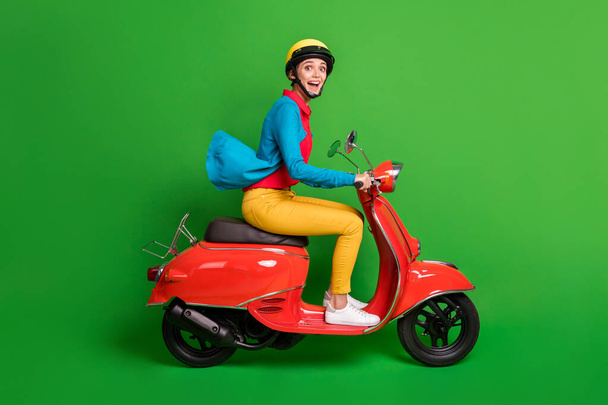 Full size profile side photo of young excited happy joyful girl look camera ride red motorcycle isolated on green color background - Φωτογραφία, εικόνα