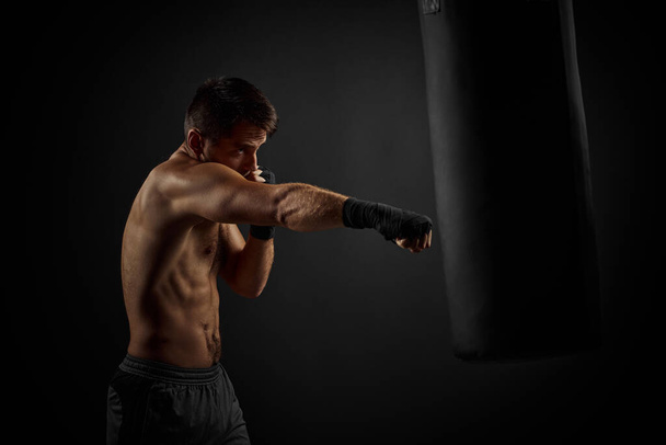 Male boxer punching in boxing bag - Foto, immagini