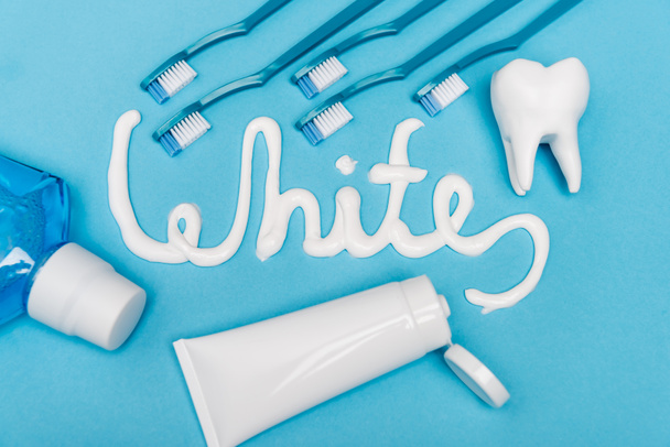 Visão superior de letras brancas de pasta de dentes, enxaguatório bucal e escovas de dentes no fundo azul - Foto, Imagem