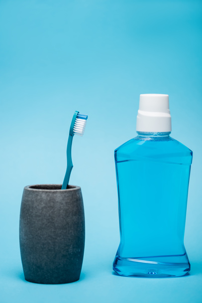 Egy üveg szájvíz közel fogkefe kék háttér - Fotó, kép
