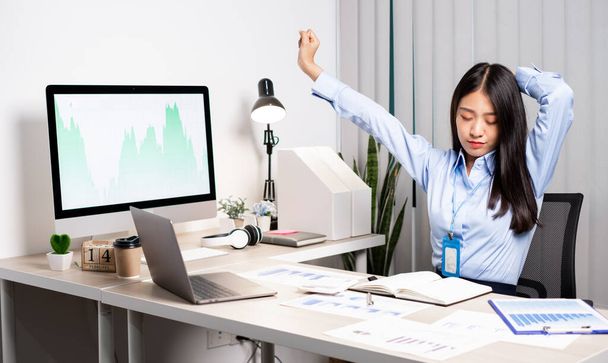 Asiatique femme comptable est fatigué de travailler dans une chaise, étirement pour se détendre et se détendre tout en travaillant dur au bureau. - Photo, image