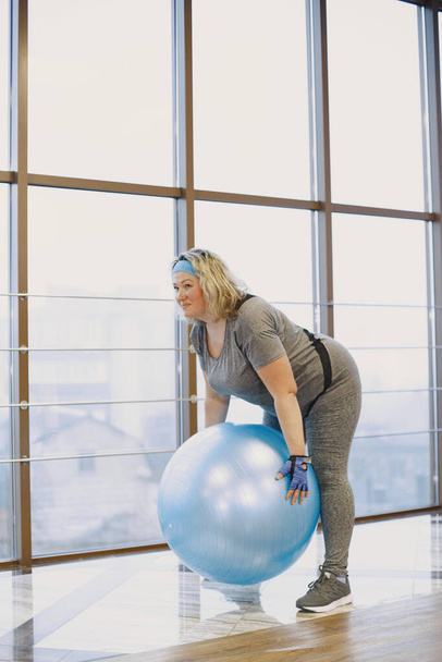 Adult fat woman doing gymnastics at the gym - Фото, изображение