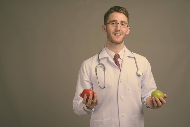 Young handsome man doctor wearing eyeglasses against gray background - Photo, Image