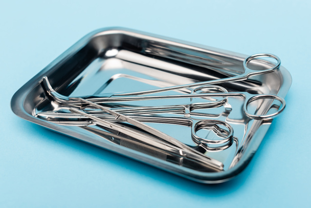 Close up view of stainless dental tools in tray on blue background - Фото, изображение