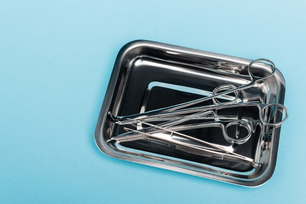 Top view of dental tools and tweezers in tray on blue background - Photo, Image