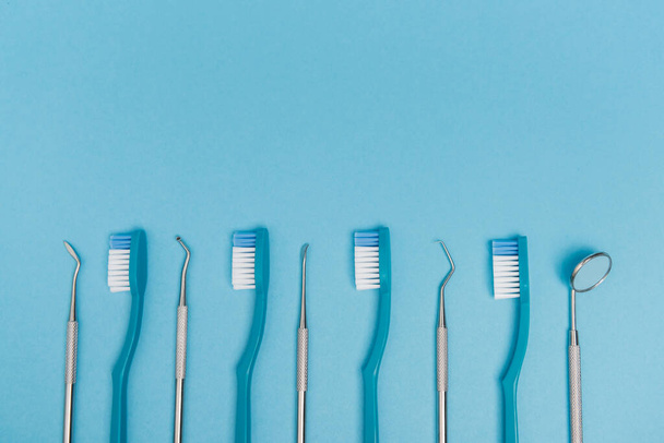 Vista dall'alto di spazzolini da denti e strumenti dentali su sfondo blu con spazio di copia  - Foto, immagini