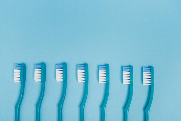 Bovenaanzicht van blauwe tandenborstels op blauwe achtergrond met kopieerruimte  - Foto, afbeelding