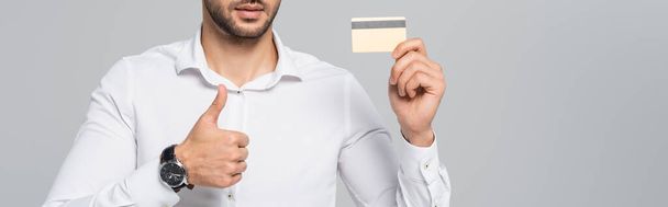 cropped view of manager with credit card showing thumb up isolated on grey, banner - Foto, Bild