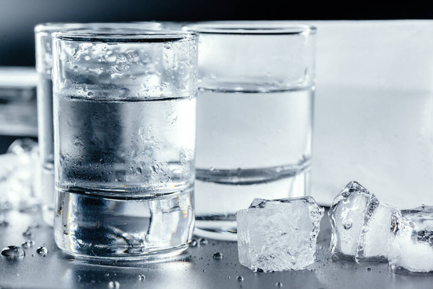 Cold vodka in shot glasses on a black background. - Photo, image