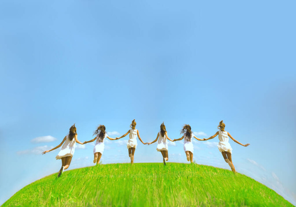 six running girls  at green grass at background of blue sky with clouds. 6 young adult women  on summer field. Empty space for inscription. Back view. No faces. Girlfriend concept. round planet Earth. - Φωτογραφία, εικόνα