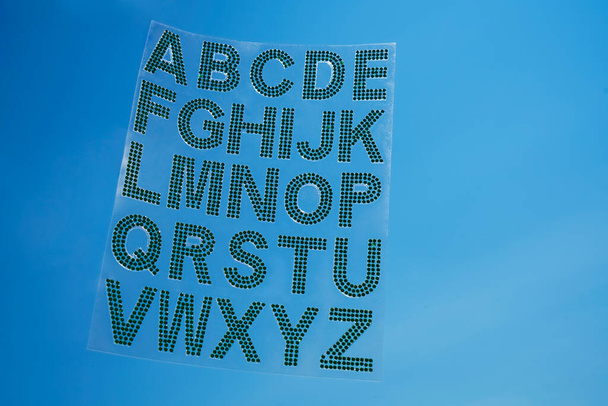 Set - the English alphabet from green rhinestones on blue sky background. ABC - Fotoğraf, Görsel