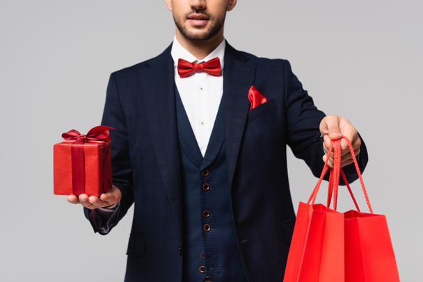 partial view of elegant man in blue suit holding valentines day gifts isolated on grey - Foto, Imagen