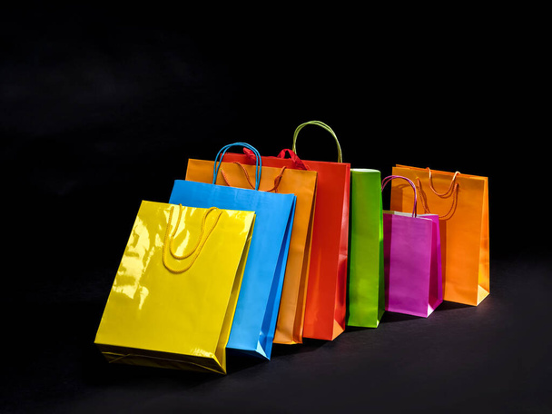 Πολύχρωμες χάρτινες σακούλες για ψώνια και δώρα. Online πωλήσεις έννοια. Αγαθά προς πώληση. Μαύρο φόντο. - Φωτογραφία, εικόνα