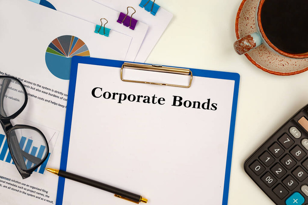 Desktop office desk, notebook, glasses, pen and documents with Corporate Bonds on a tabl - Photo, image