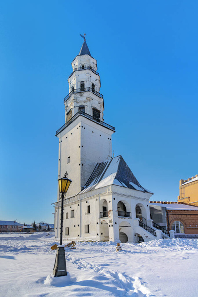 tower in Nevyansk (Russia) in winter. The old leaning tower known to tourists all over the world against the blue sky on a clear frosty day. nearby the lantern also bowed its "head". white pure snow - Φωτογραφία, εικόνα